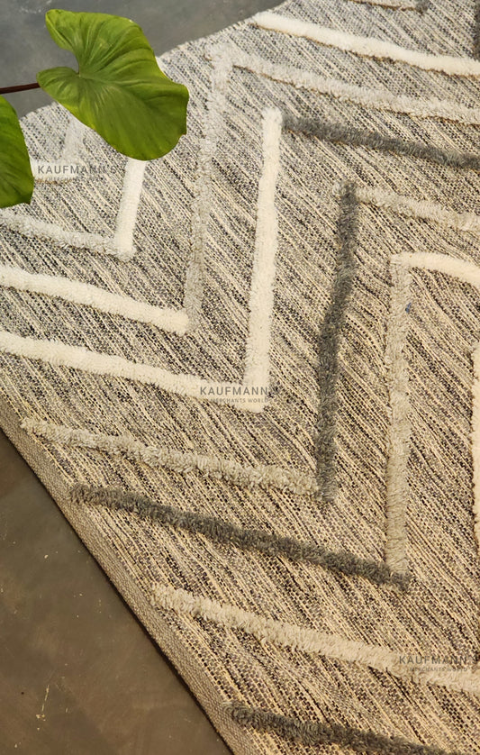 A multicolored geometric-patterned cotton rug with a jute leaf on top, showcasing a textured design.