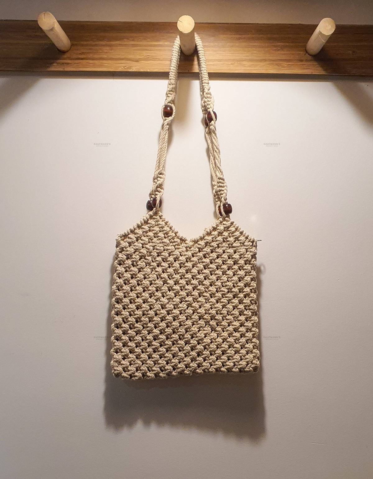 Woven handbag hanging on a wooden rack against a white wall