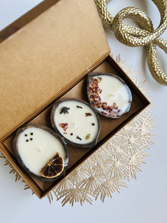 Three small candles with decorative elements in a brown box on a white background