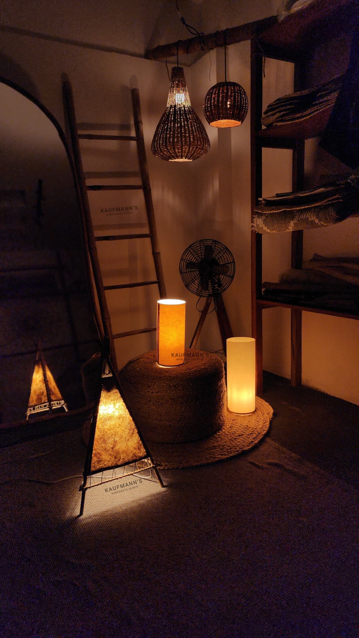 Bamboo hanging lampshades, banana fiber lampshades and paper lampshades displayed in a dark setting with a view of the shop interior showcasing eco-friendly lighting designs