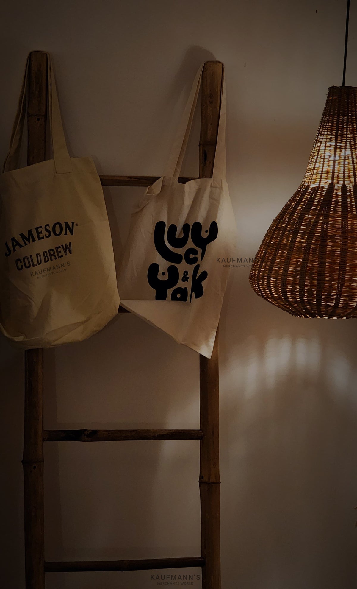 Aesthetic store ambience with two hanging white cotton tote bags displayed alongside handmade lampshades, showcasing eco-friendly lifestyle products.