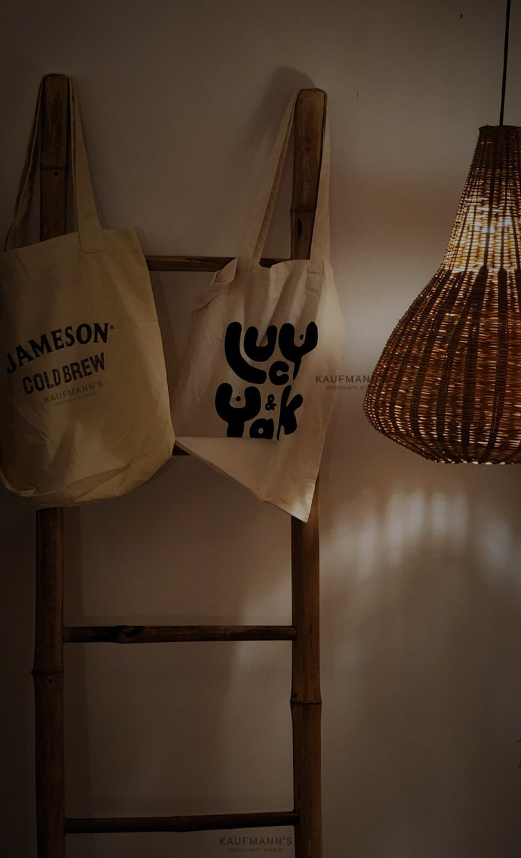 Aesthetic store ambience with two hanging white cotton tote bags displayed alongside handmade lampshades, showcasing eco-friendly lifestyle products.
