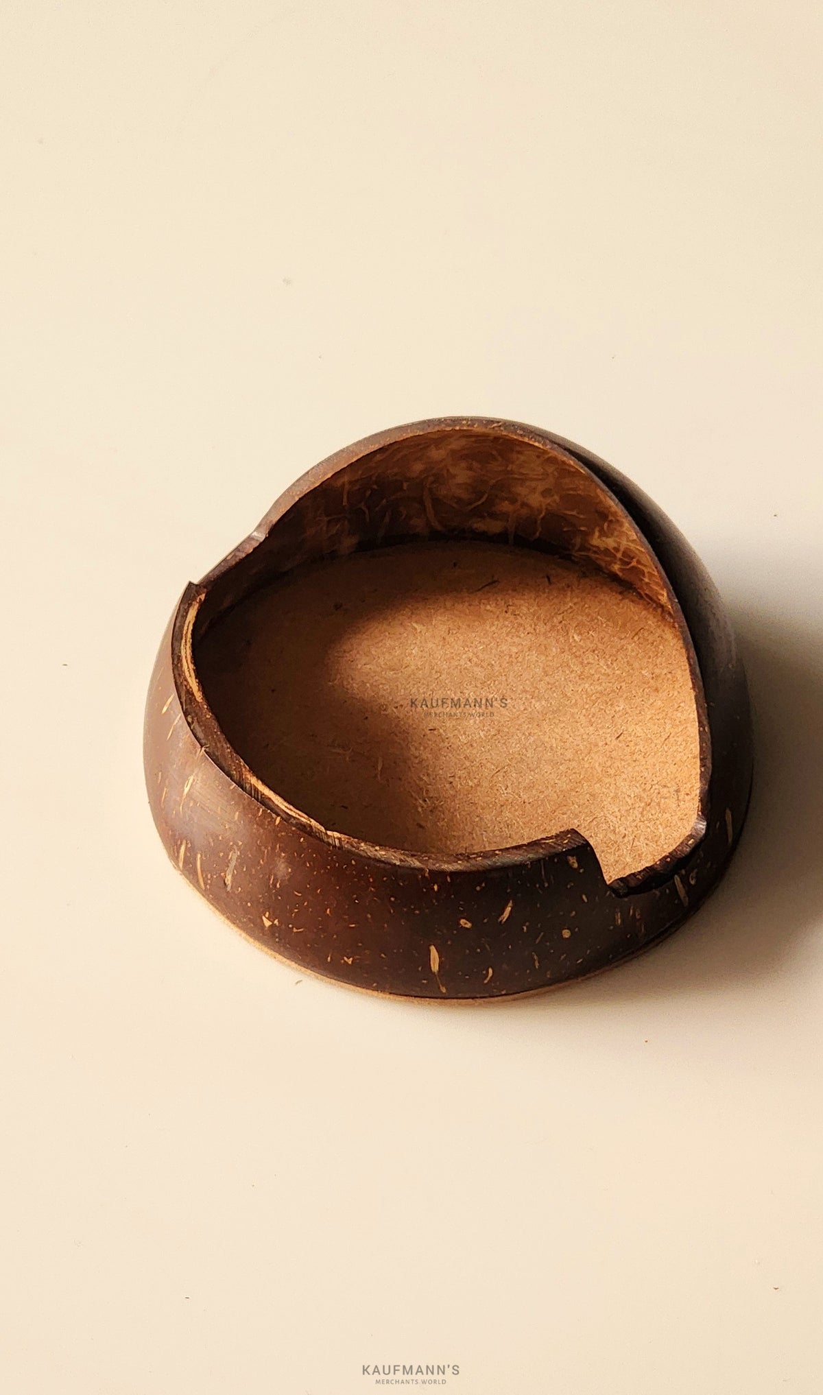 A coconut shell phone holder with a smooth, polished finish, displaying an oval shape with a visible crack on the side.
