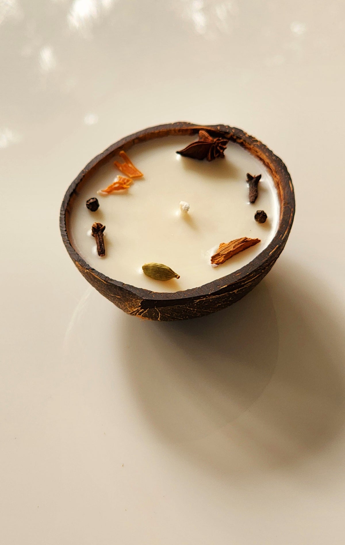 Scented candle made with coconut shell poured along with aroma of Spices.