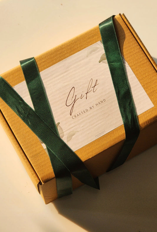 A corporate gift hamper box tied with a green ribbon, featuring a handmade product label.
