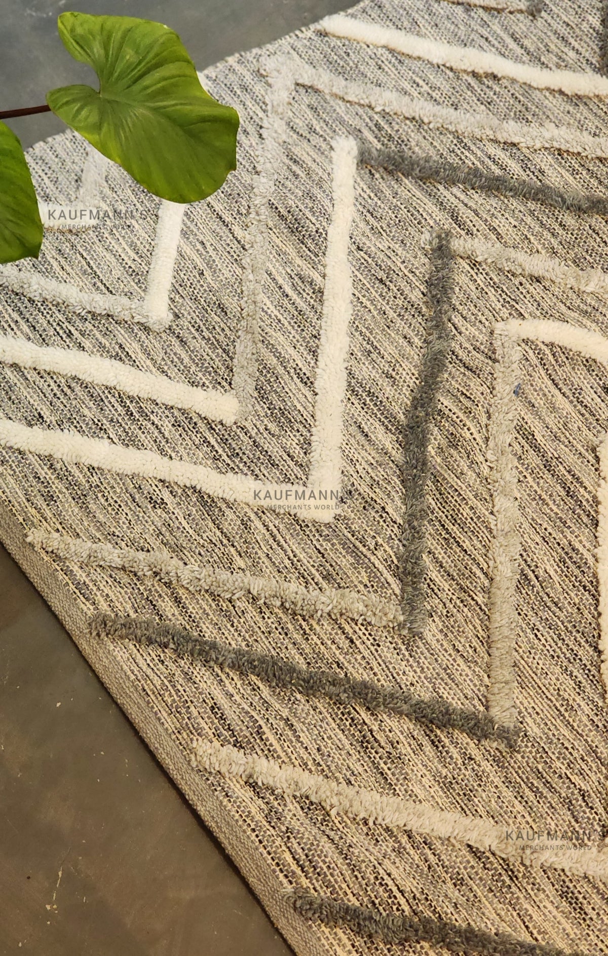 A multicolored geometric-patterned cotton rug with a jute leaf on top, showcasing a textured design.