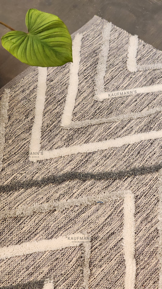 A multicoloured geometric-patterned cotton rug with a jute leaf on top, showcasing a textured design.