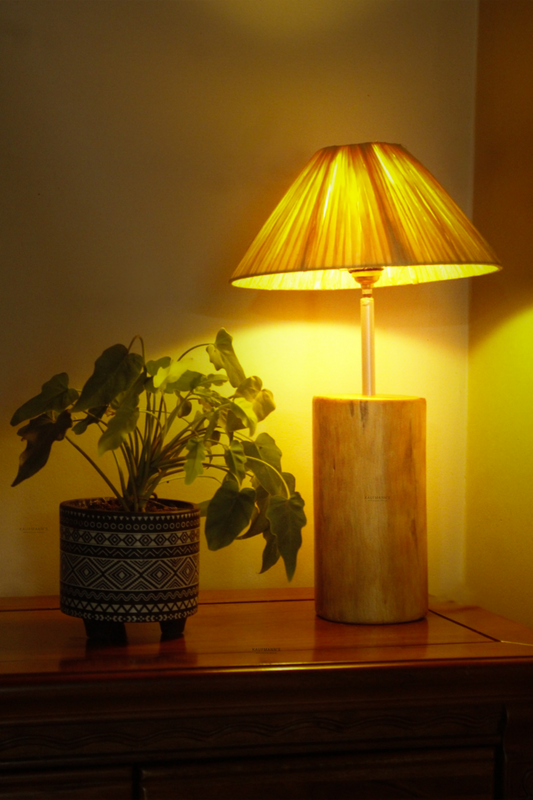 Raffia Wooden Table Lamp with a yellow shade and a potted plant on a wooden surface.