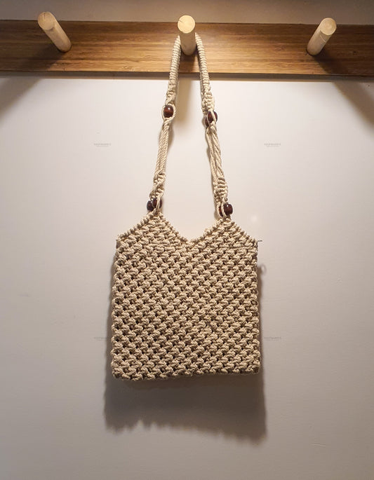 Woven handbag hanging on a wooden rack against a white wall