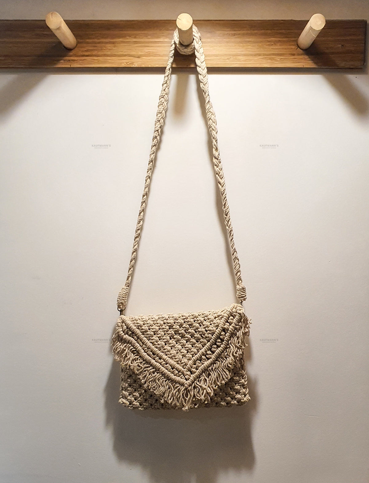 Woven handbag hanging on a wooden hook against a white wall