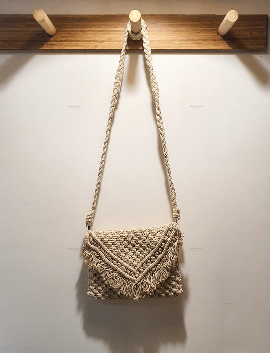 Woven handbag hanging on a wooden hook against a white wall