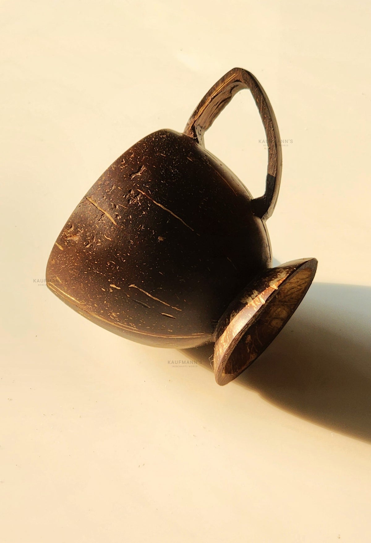 A brown coconut shell cup with a handle, displayed on a light background.